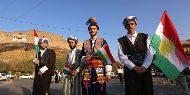 Iraqis dressed in traditional clothing and holding Kurdish flags walk near the citadel in Arbil, the capital of the autonomous Kurdish region of northern Iraq, as they head to a gathering to urge people to vote in the upcoming independence referendum on September 13, 2017. Iraq's autonomous Kurdish region will hold a historic referendum on statehood in September 2017, despite opposition to independence from Baghdad and possibly beyond. / AFP PHOTO / SAFIN HAMED (Photo credit should read S