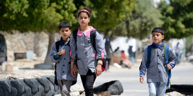 Tunisian school children walk past on April 14, 2016 a road block set up by residents of the island of Kerkennah during a series of social protests related to Tunisia's natural gas facility of UK based oil company Petrofac. Petrofac facility on Kerkennah has halted production since social protests started in January 2016. / AFP / FETHI BELAID (Photo credit should read FETHI BELAID/AFP/Getty Images)