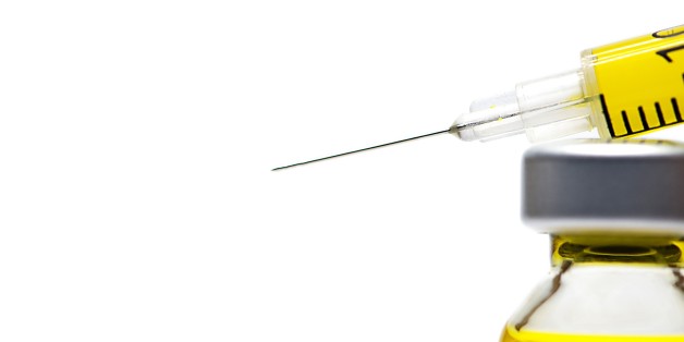 Syringe with yellow fluid on a white background