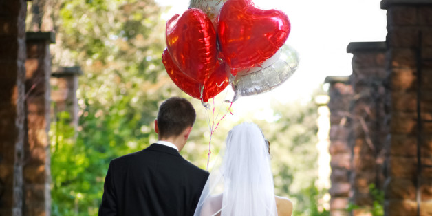 Bridal couple walking a lonely path with heart shaped balloons.