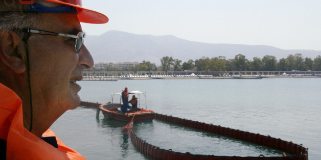 A member of Greece's Environmental Protection Engeneering corporation oversees the containment of a mock oil spill at the Olympic Sailing Complex of Agios Kosmas in Athens, June 25, 2004. The exercise was held in preparation for the upcoming Athens Olympic. REUTERS/John Kolesidis. JK