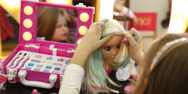 A young girl paints the face of a doll by the company Simba during the press preview of the 66th International Toy Fair in Nuremberg January 27, 2015. More than 2,700 exhibitors from over 60 countries worldwide will present their new toy products from January 28 to February 2, 2015. REUTERS/Michaela Rehle (GERMANY - Tags: SOCIETY BUSINESS)