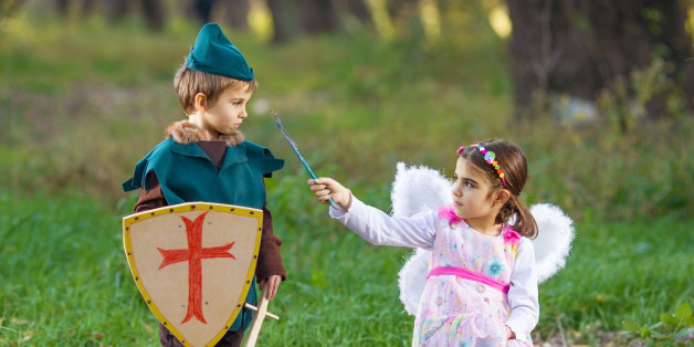 Cute little children dressed up as a fairy and a knight playing in a forest