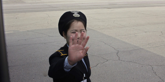 A ground staff of North Korean airliner Air Koryo thrusts a hand in front of her face at the airport in North Korean capital of Pyongyang October 12, 2010. REUTERS/Petar Kujundzic (NORTH KOREA - Tags: POLITICS TRANSPORT)