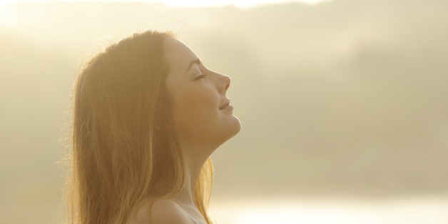 Backlight profile of a woman breathing deep fresh air in the morning sunrise isolated in white above