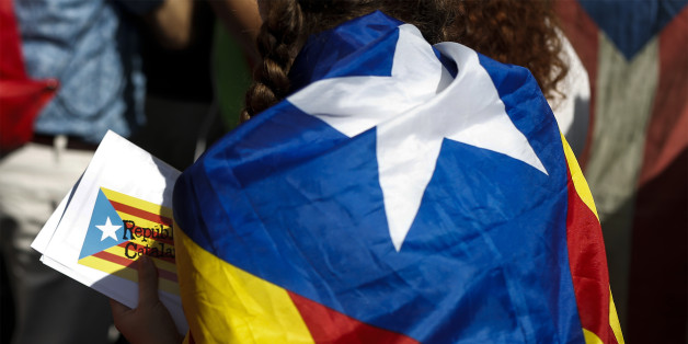 A supporter of Catalan independence wears a flag over their shoulders during a demonstration called for by the Catalan National Assembly (ANC) and Omnium Cultural outside the University of Barcelona, in Barcelona, Spain, on Sunday, Sept. 24, 2017. Spains struggle to stop Catalonias separatist referendum overcame a potential body blow over the weekend as the regions police force acceded to demands it take more direction from the central government in Madrid. Photographer: Pau Barrena/Bloomberg via Getty Images