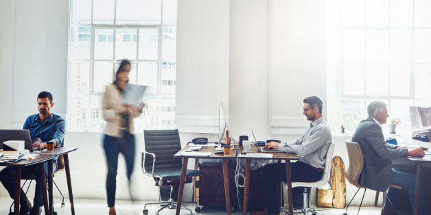 Blurred motion shot of mature businessman using a computer at work in a busy office