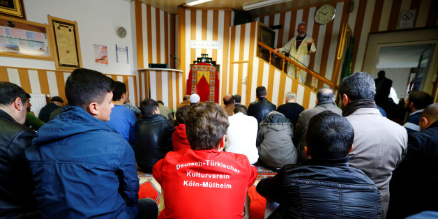 Young Muslims listen to a Turkish imam during Friday prayers at the Turkish Kuba Camii mosque located near a hotel housing refugees in Cologne's district of Kalk, Germany, October 14, 2016. Picture taken October 14, 2016. Youth in foreground wears a shirt reading, "German-Turkish culture club Cologne-Muehlheim". Picture taken October 14, 2016. To match Insight EUROPE-MIGRANTS/GERMANY-MOSQUES REUTERS/Wolfgang Rattay
