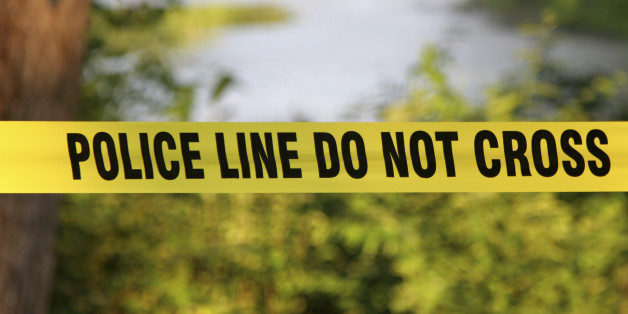 Police Do Not Cross aa yellow plastic tape in a forest.