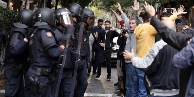 People raise their arms in front of Spanish police after the seizure of ballot boxes in a polling station in Barcelona, on October 1, 2017, on the day of a referendum on independence for Catalonia banned by Madrid.More than 5.3 million Catalans are called today to vote in a referendum on independence, surrounded by uncertainty over the intention of Spanish institutions to prevent this plebiscite banned by justice. / AFP PHOTO / PAU BARRENA (Photo credit should read PAU BARRENA/AFP/Getty I