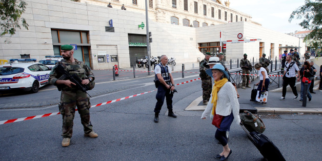 Travellers walk past French police and soldiers who secure a street near the Saint-Charles train station (Rear) after French soldiers shot and killed a man who stabbed two women to death at the main train station in Marseille, France, October 1, 2017. REUTERS/Jean-Paul Pelissier