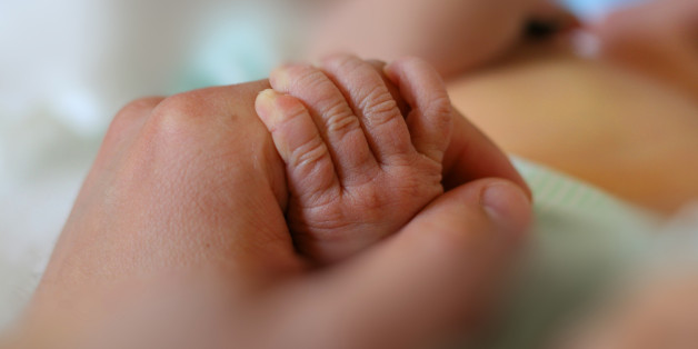 Newborn baby little hand hold by adult man hand of his father