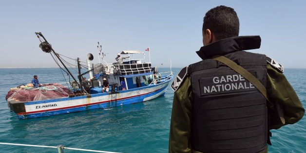TO GO WITH AFP STORY BY KAOUTHER LARBI A member of the Tunisia's national guard stops a fishing boat in the sea bordering Tunisia and Libya as they check vessels for illegal migrants trying to reach Europe on May 5, 2015 off the coast of Tunisia's southeast port of Zarzis. Already on high alert along the border because of the chaos and security problems that plague neighbouring Libya, Tunisian authorities are now faced with responding to a growing number of distress calls off the coast as increa