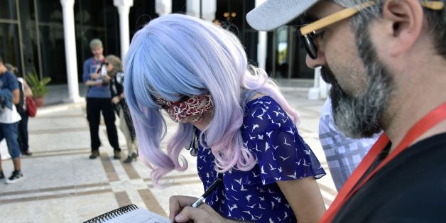 An Algerian man sketches as he speaks to a young woman at the International Festival of Comics of Algeria (FIBDA) in Algiers on October 3, 2017. / AFP PHOTO / RYAD KRAMDI (Photo credit should read RYAD KRAMDI/AFP/Getty Images)