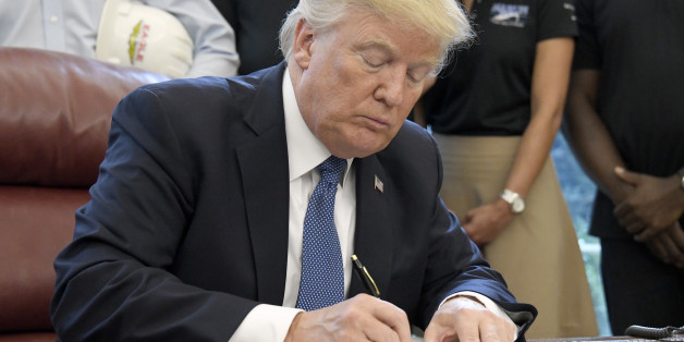 U.S. President Donald Trump, center, signs the National Manufacturing Day proclamation in the Oval Office of the White House in Washington, D.C., U.S., on Friday, Oct. 6, 2017. Trump signed a proclamation honoring National Manufacturing Day and said his administration is helping 'compete and win on the world stage.' Photographer: Ron Sachs/Pool via Bloomberg