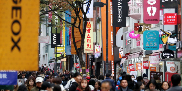 People walk past stores at the Myeongdong shopping district in Seoul, South Korea, on Monday, Oct. 31, 2016. As South Korean President Park Geun-hye's popularity plummets, members of her own party are publicly demanding action to staunch the bleeding from an influence-peddling scandal. Photographer: SeongJoon Cho/Bloomberg via Getty Images