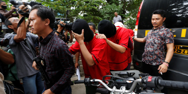 A plainclothes policeman holds a rifle as he escorts suspects during a police investigation into a men's club after a weekend raid on what authorities described as a "gay spa" in Jakarta, Indonesia, October 9, 2017. REUTERS/Beawiharta
