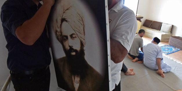 Members of Algeria's small Ahmadi community put up a photo of Mirza Ghulam Ahmad (1835-1908) the founder of the Ahmadiyya movement, a reformist Islamic movement which is accused of heresy by Islamist extremists and targeted by the authorities, at a house in Tilpasi, west of Algiers, on June 30, 2017.
Founded in late 19th-century India, the Ahmadiyya movement follows the teachings of Mirza Ghulam Ahmad, an Indian Muslim they believe to be the long-awaited Islamic messiah. It is anathema to traditional Islamic thinking, and Ahmadis living in many Muslim-majority countries have faced persecution and physical violence.
/ AFP PHOTO / RYAD KRAMDI (Photo credit should read RYAD KRAMDI/AFP/Getty Images)