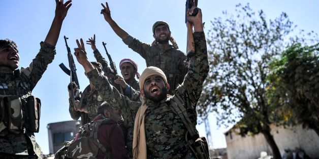 TOPSHOT - Members of the Syrian Democratic Forces (SDF), backed by US special forces, celebrate at the frontline in the Islamic State (IS) group jihadists crumbling stronghold of Raqa on October 16, 2017 US-backed fighters battled hundreds of Islamic State group jihadists holed up in the last pockets of Syria's Raqa, as the former extremist stronghold stood on the verge of capture. / AFP PHOTO / BULENT KILIC (Photo credit should read BULENT KILIC/AFP/Getty Images)