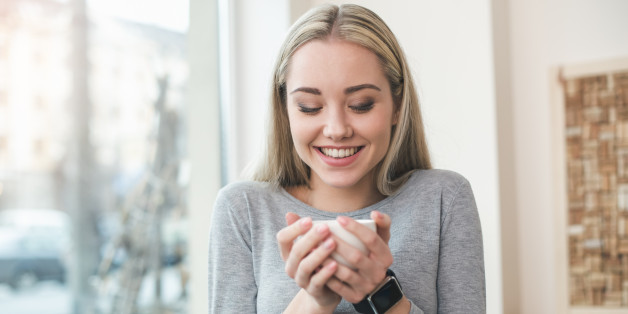 Image of young and pretty woman with cup of coffee laughing in cafe