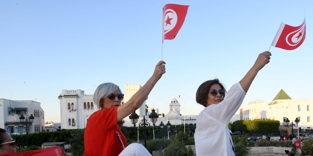 Tunisians hold flags during a demonstration in solidarity with Prime Minister Youssef Chahed in his fight against corruption on May 26, 2017 in front of the prime ministry offices. Tunisian authorities froze the assets of eight businessmen suspected of corruption, including some already under house arrest. Tunisia declared a 'war on corruption' this week after the arrest of three businessmen and a customs officer on suspicion of graft and financing protests in the North African country. / AFP PH