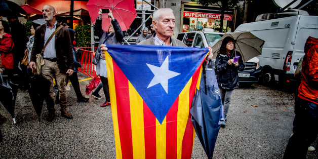 BARCELONA, CATALONIA, SPAIN - 2017/10/19: A man is seen while holding a flag of Catalonia front of the Government Delegation.Despite the heavy rains hundred of people gathered front of the Spanish Government Delegation in Barcelona to demand freedom for the two political prisoners Jordi Cuixart and Jordi SÃ nchez. This action falls within the days of demonstrations and actions that will take place during the next few weeks due to the application of article 155 that suspends the autonomy and th