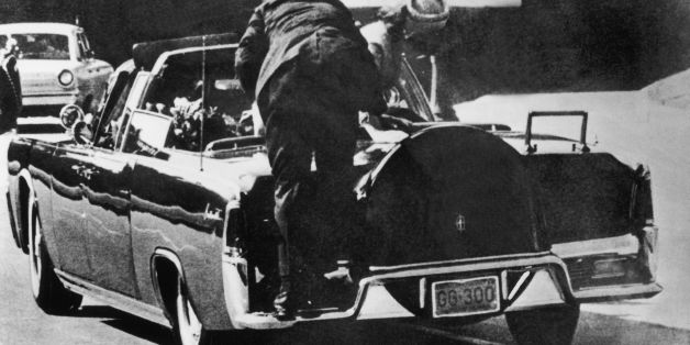 UNITED STATES - NOVEMBER 22: November 22, 1963. Just after John F. KENNEDY, president of the United States, has been hit by bullets, Jacqueline KENNEDY stands up in the presidential car to lift up the body of her husband. In the foreground, the body guard riding on the back fender leans toward them. (Photo by Keystone-France/Gamma-Keystone via Getty Images)