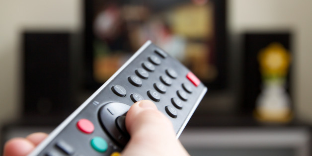 Human hand holding remote control changing Channels with television set.