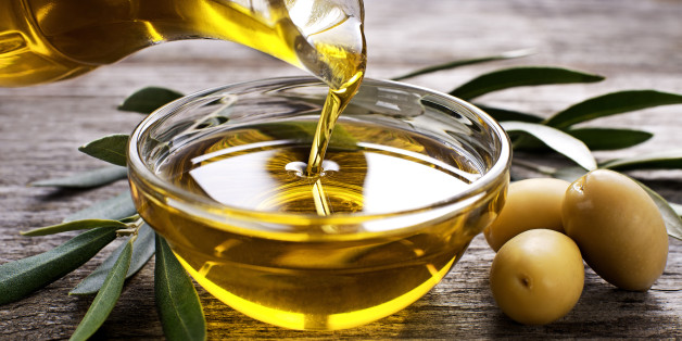 Bottle pouring virgin olive oil in a bowl close up