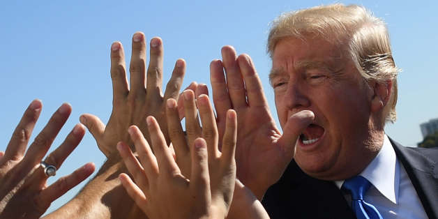 TOPSHOT - US President Donald Trump receives high-fives from students as he arrives at Dallas Love Field in Dallas, Texas, on October 25, 2017. / AFP PHOTO / JIM WATSON (Photo credit should read JIM WATSON/AFP/Getty Images)