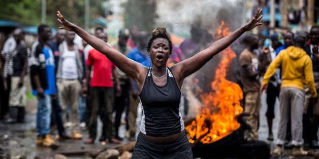 An opposition supporter reacts under the heavy rain in front of a burning barricade in Mathare district, in Nairobi on October 26, 2017, as a group of demonstrators blocked the road and tried to prevent voters from accessing a polling station during presidential elections.Kenyans trickled into polling stations on October 26 for a repeat election that has polarised the nation, amid sporadic clashes as supporters of opposition leader ignored his call to stay away and tried to block voting. / AFP P