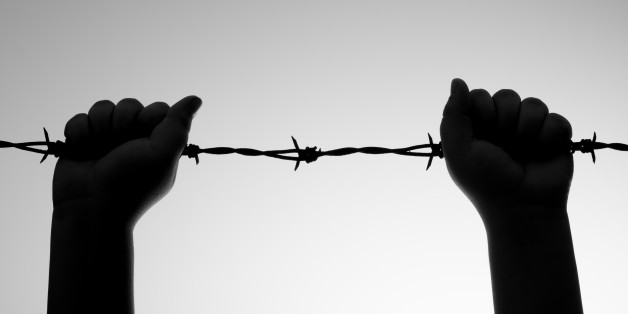 Backlit Black and White image of a child holding onto barbed wire offering a concept of child abuse and social issues.