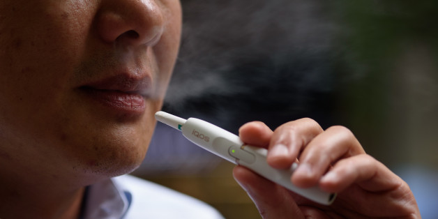 A man smokes a Philip Morris International Inc. iQOS electronic cigarette in this arranged photograph in Tokyo, Japan, on Tuesday, Aug. 23, 2016. Philip Morris International and Japan Tobacco Inc. have rolled out products that are heated -- not burned -- in battery-charged devices, seeking to appeal to smokers who want their nicotine fix without the usual smell and smoke. Photographer: Akio Kon/Bloomberg via Getty Images