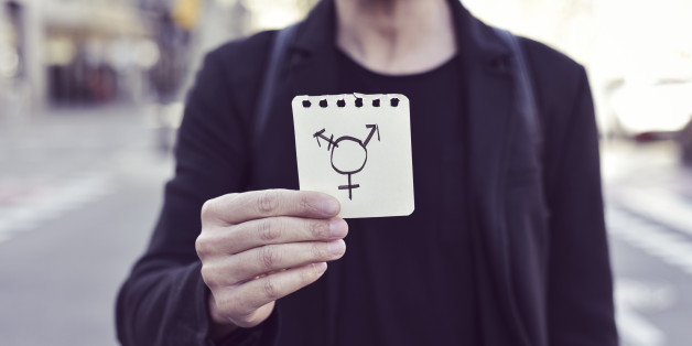 closeup of a young Caucasian man in the street showing a piece of paper with a transgender symbol drawn in it