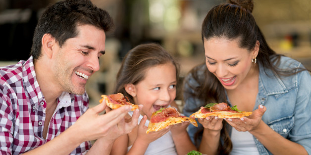 Happy Latin American family eating pizza at a restaurant - food and drinks concepts
