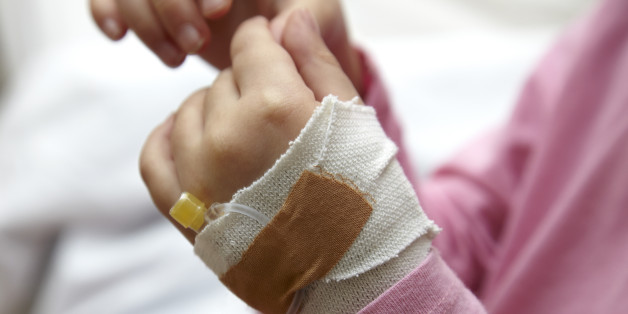 Little girl in hospital with an IV drip line. Only her hands can be seen. Full frame shot, horizontal.