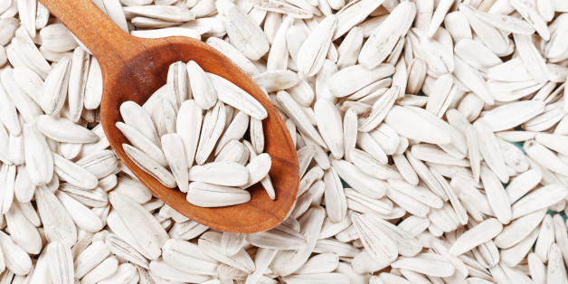 a lot of white sunflower seeds, scattered, seeds are a wooden spoon