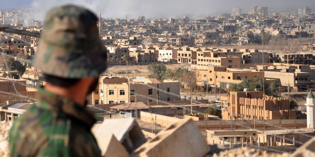 A Syrian pro-government member watches as smoke rises from buildings following an air strike by government forces in the eastern city of Deir Ezzor, on October 31, 2017, during an operation against Islamic State (IS) group jihadists.The Assad regime has been able to recapture more than half of Syria's territory with the support of Russian air strikes. It is now focusing on the oil-rich eastern province of Deir Ezzor, where the SDF alliance is also involved. / AFP PHOTO / STRINGER (Photo c