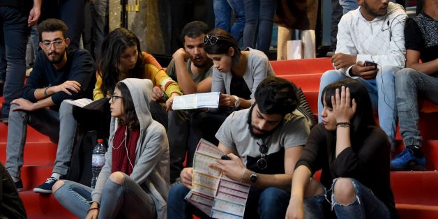 Tunisian youths check the programme as they wait outside a movie theatre during the Carthage Film Festival in Tunis' seaside suburb of Carthage on November 2, 2016.The Carthage film festival will run from from October 28 to November 5. / AFP / FETHI BELAID (Photo credit should read FETHI BELAID/AFP/Getty Images)