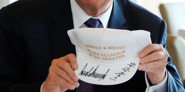 U.S. President Donald Trump holds a hat he and Japan's Prime Minister Shinzo Abe signed, reading "Donald & Shinzo Make Alliance Even Greater" before lunch and a round of golf at Kasumigaseki Country Club in Kawagoe, Japan November 5, 2017. REUTERS/Jonathan Ernst