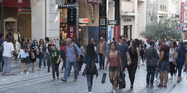 Street atmosphere from Ermou Boulevard in Athens, Greece. You can see multiple people walking on the pedestrian area, with shops all over around.