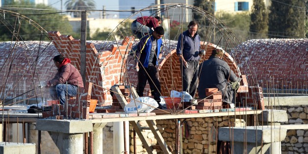 Tunisian builders work at the construction site of a new marketplace on December 15, 2015, in the impoverished central town of Sidi Bouzid, three days ahead of the fifth anniversary of the self-immolation of Mohamed Bouazizi, a young street vendor, which sparked the revolution that ousted a dictator and ignited the Arab Spring. Five years after triggering the Arab Spring, Tunisians doggedly pursue a democratic transition while other countries remain gripped by violence and repression. AFP PHOT