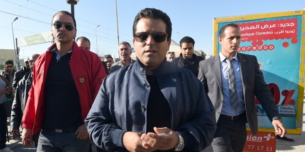 Tunisian presidential candidate and founder of the Free Patriotic Union Slim Riahi (C) arrives at a bus station during a campaign tour on November 19, 2014 in Tunis. Tunisia holds its first multi-candidate presidential election on November 23 in the final stage of a post-revolution transition that has set it apart from the turmoil of other Arab Spring states. AFP PHOTO/FETHI BELAID (Photo credit should read FETHI BELAID/AFP/Getty Images)