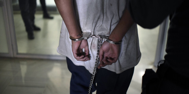 A handcuffed inmate of the Stage II Male Juvenile Detention Center, is escorted as he arrives for a hearing at a court in Guatemala City on March 21, 2017. Two of four guards freed during a police raid after being taken hostage at a Guatemala juvenile detention center have died. The raid occurred Monday after 40 gang-member inmates in the Stage II facility outside Guatemala City rioted a day earlier, killing two guards and grabbing the four hostages, who were badly wounded. / AFP PHOTO / JOHAN