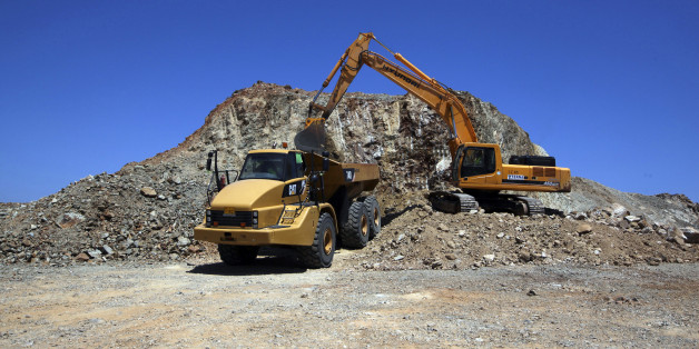 A digger and an earth moving truck are seen at work on the construction site for a wind farm by Terna Energy SA, on the Greek island of St George, off of the coast of Athens, Greece, on Monday, June 11, 2012. Greece faces the threat of rolling power blackouts as the economic crisis leaves utilities without cash to pay for natural gas imports and operate power stations. Photographer: Chris Ratcliffe/Bloomberg via Getty Images