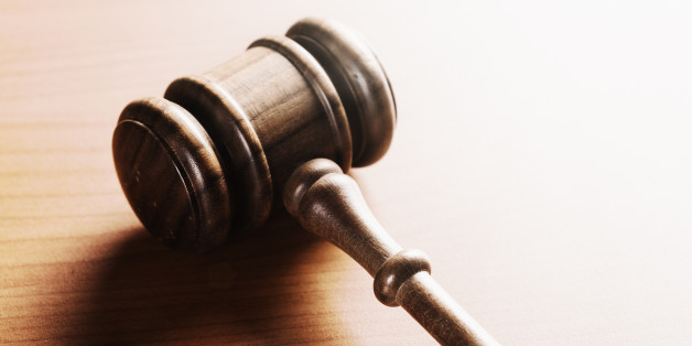 A wooden judge's or auctioneer's gavel, brightly lit, on a wooden desk with copy space.