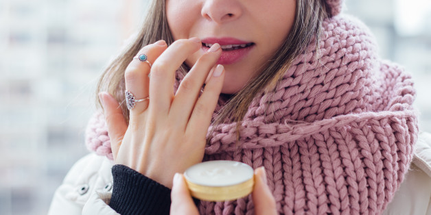Young women apply lip care balm outside, on cold weather