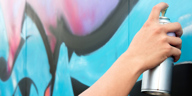 Hand holding spray paint on the wall graffiti
