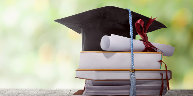 Graduation hat with degree paper on a stack of book against blurred background