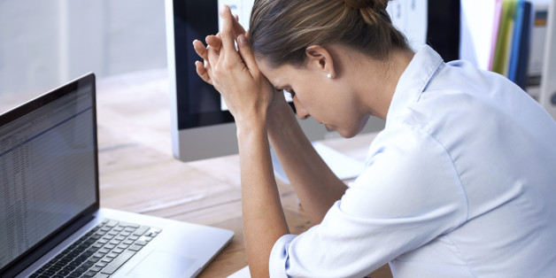 A young businesswoman sitting with her head in her hands
